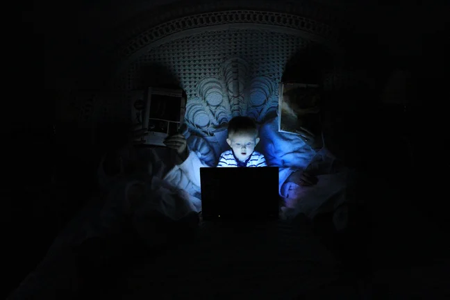 A little boy looking at a laptop with a surprised face.